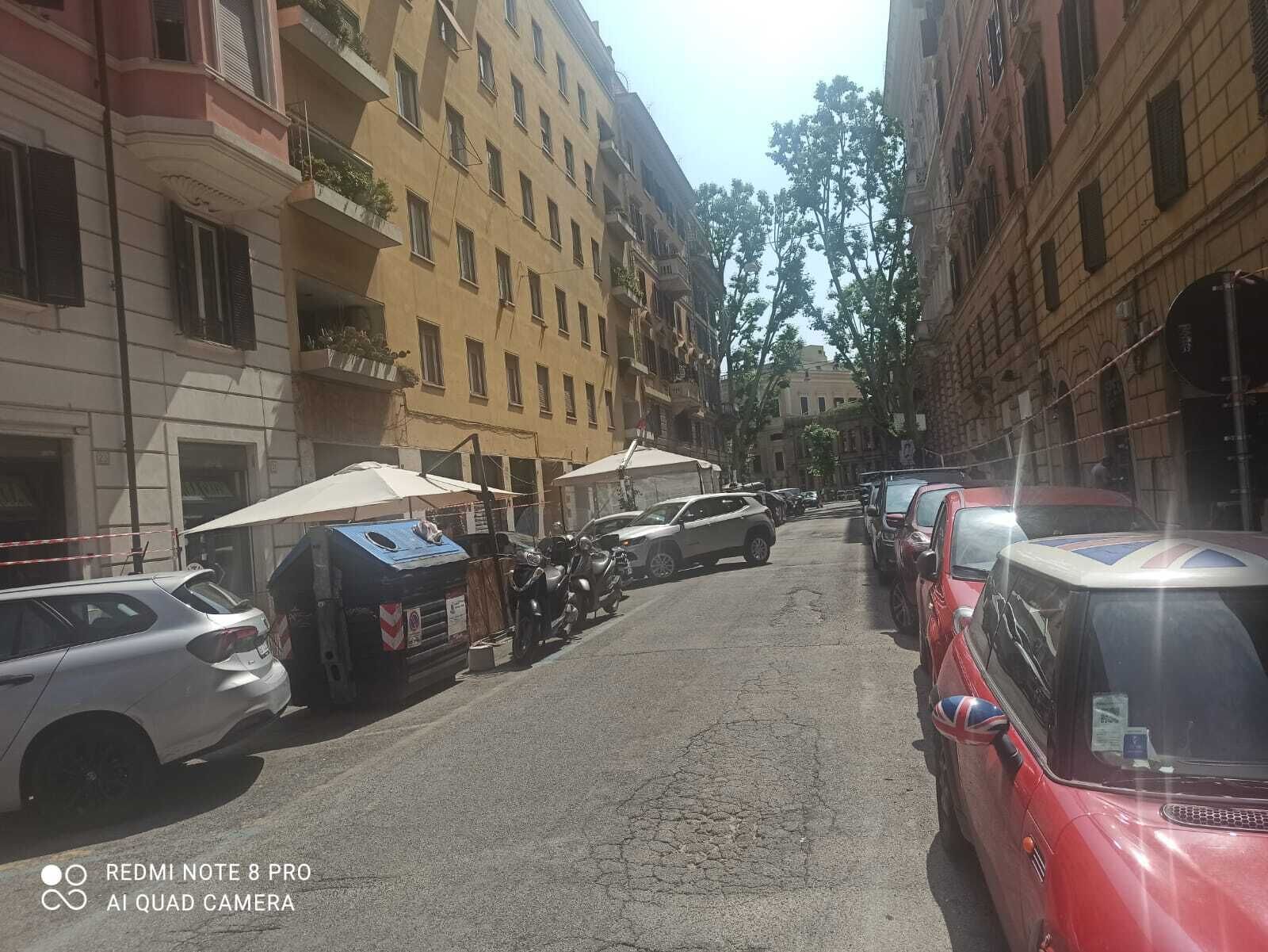 Une rue étroite bordée de voitures garées et d’immeubles.
