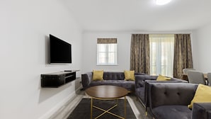 A modern living room with a flat-screen TV, a sofa set, and a round coffee table. - Stylish 4 bed 3 bath- Mill Hill (London)