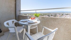 A balcony with a round table and two white chairs, overlooking a cityscape with mountains in the distance. - Apartment Miami by Interhome (Empuriabrava)