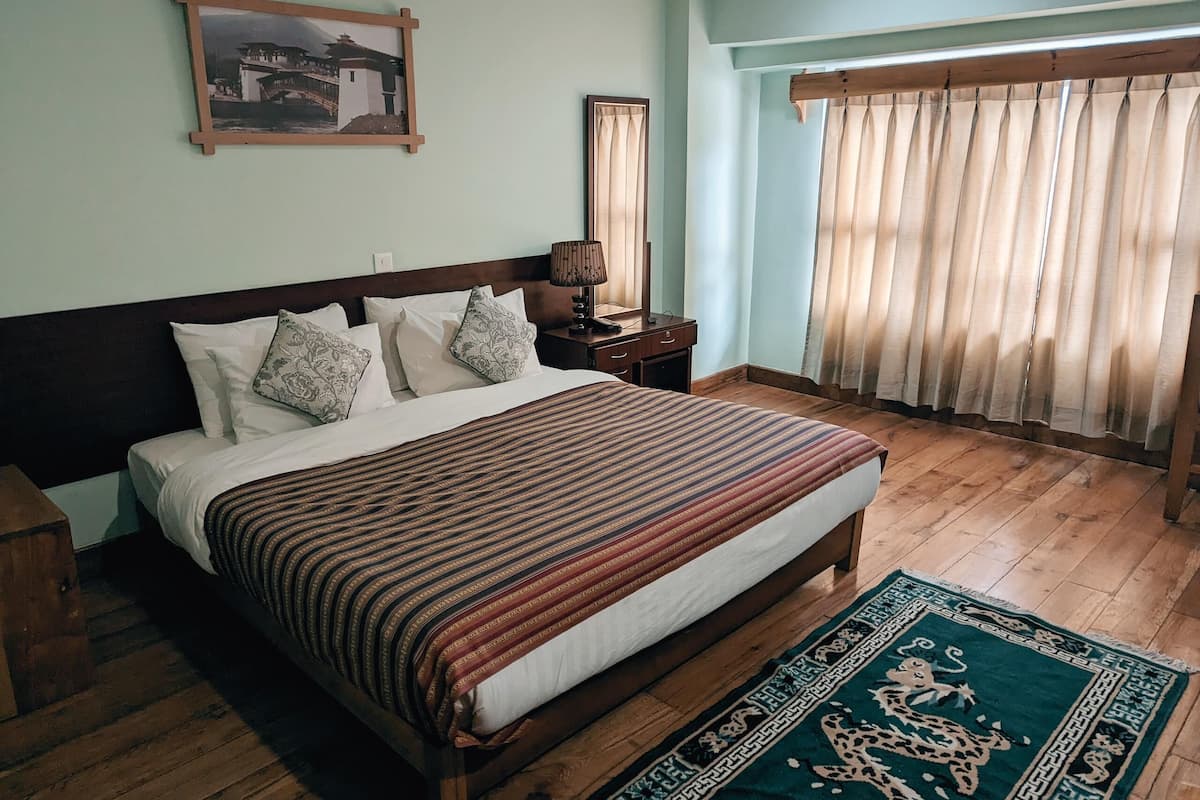 A neatly made bed with a patterned bedspread, a wooden headboard, and a nightstand with a lamp.