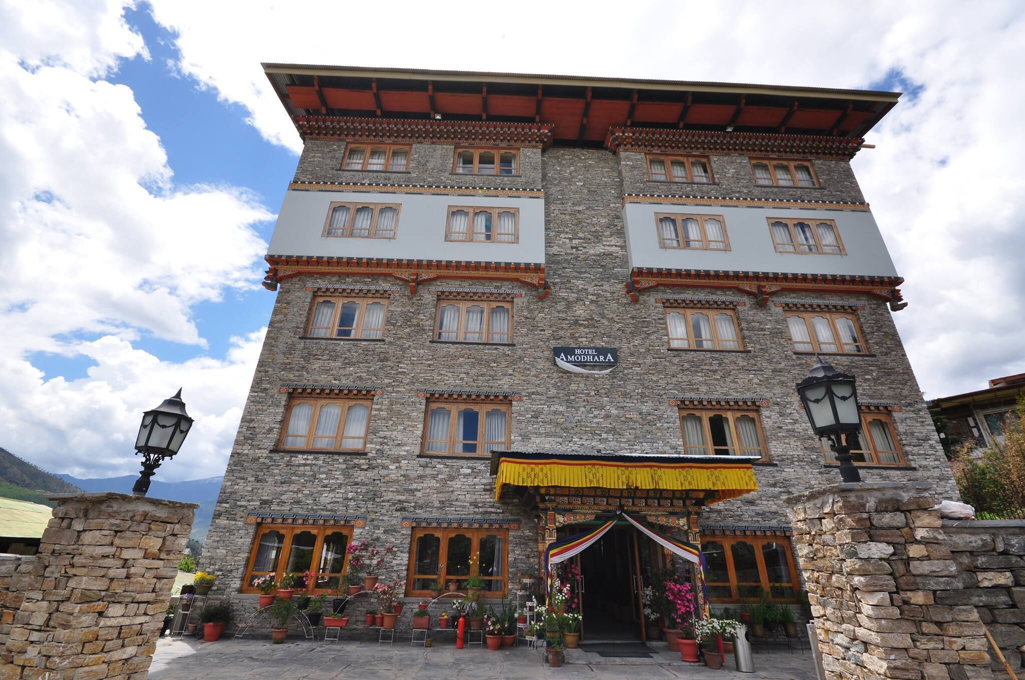 A stone building with multiple windows and a sign reading "Hotel Amodharna."