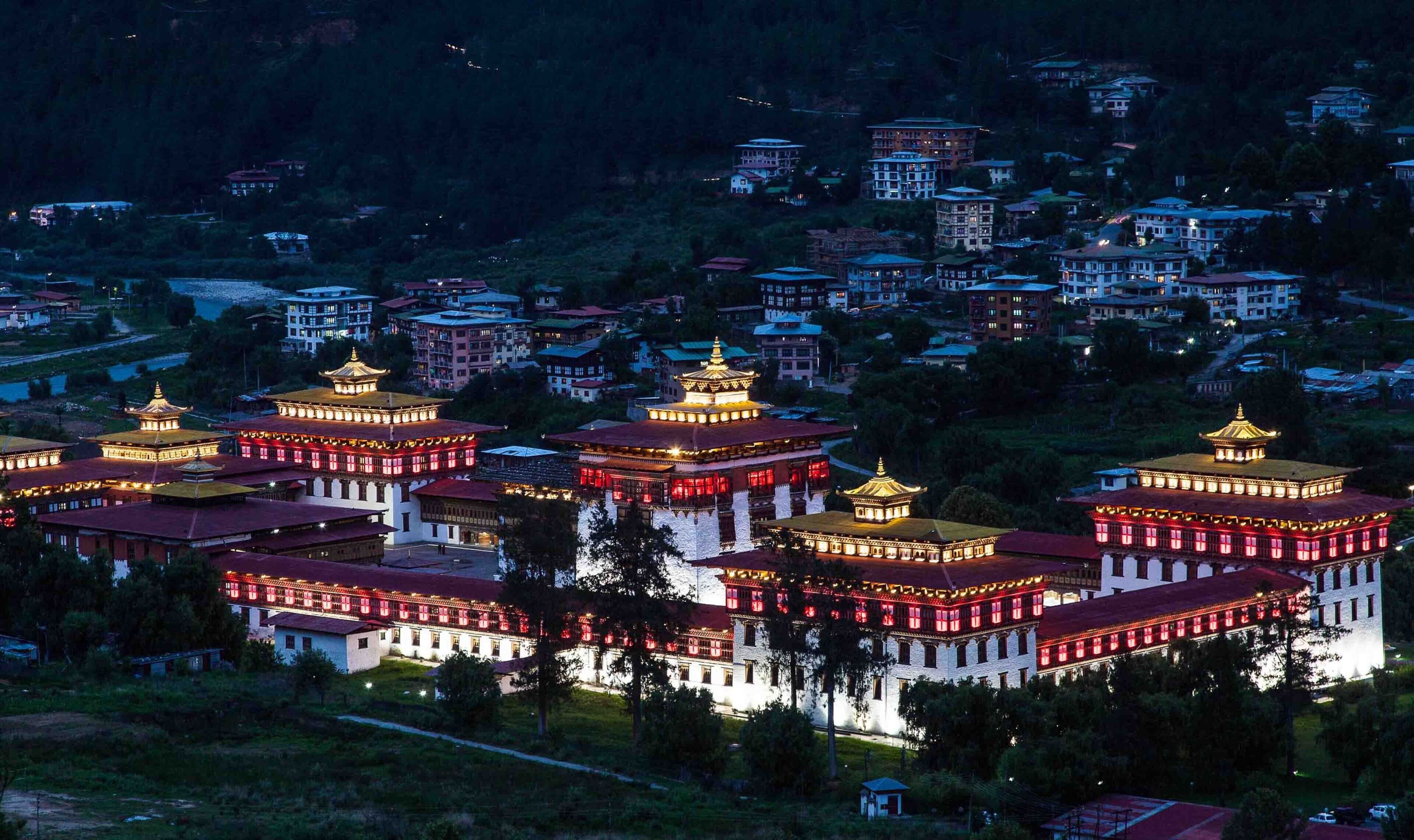 A large, multi-tiered building with traditional architecture, surrounded by smaller residential buildings.