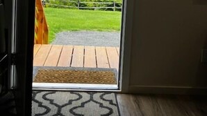 Ein Zimmer mit Holzboden, einem gemusterten Teppich und Blick auf eine grüne Landschaft mit einem Gebäude in der Ferne.