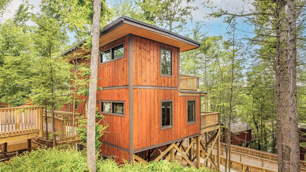 A wooden cabin with a balcony, surrounded by trees. - NEXT TO DOLLYWOOD! Treetop Cabin 2br/2ba, Private Hot Tub, Gas Grill, 2 Decks (Pigeon Forge)