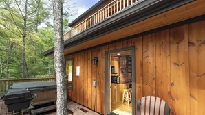 A wooden cabin with a deck, a barbecue, and a chair. - NEXT TO DOLLYWOOD! Treetop Cabin 2br/2ba, Private Hot Tub, Gas Grill, 2 Decks (Pigeon Forge)