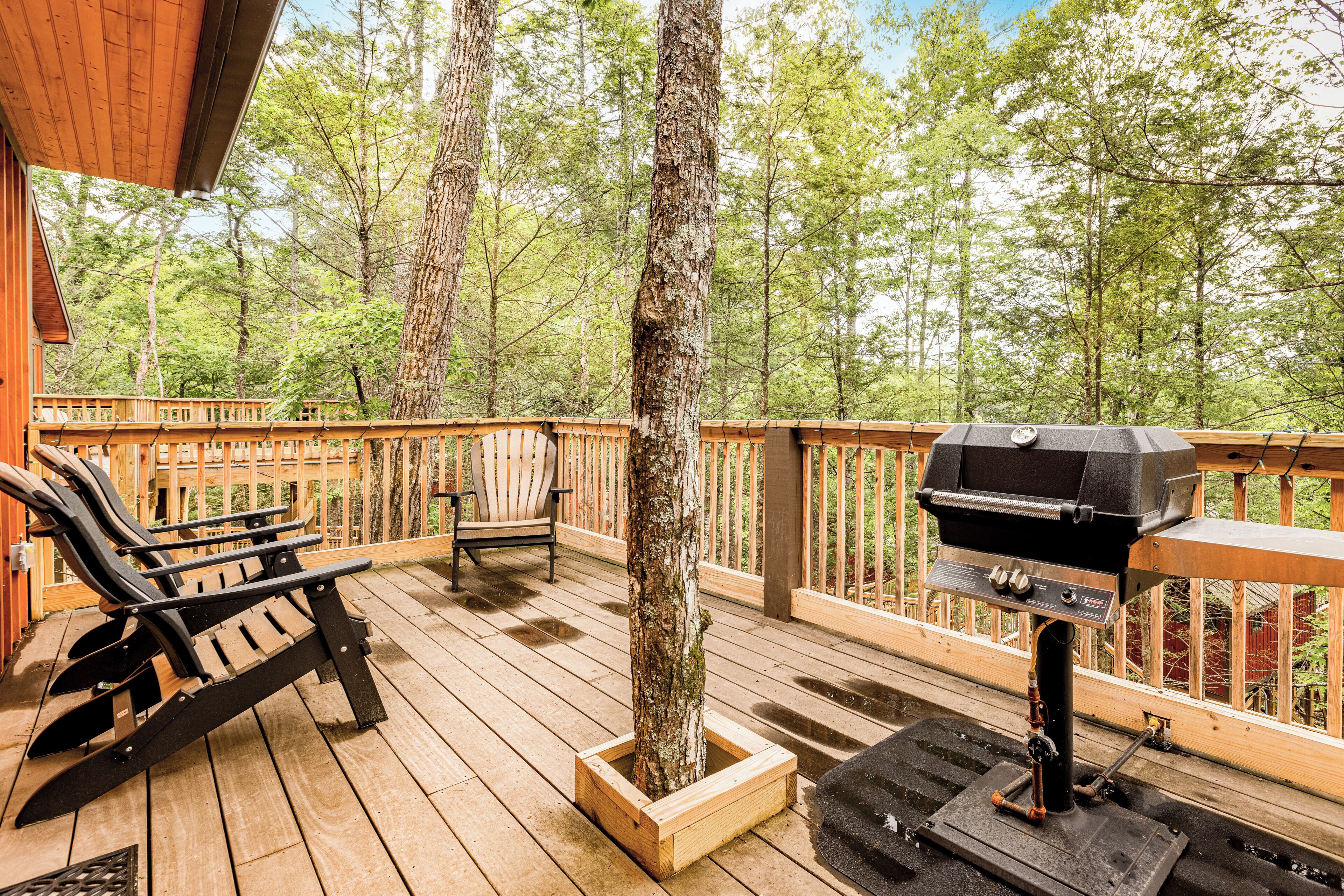 Une terrasse en bois avec un barbecue, une chaise et un jardinière.