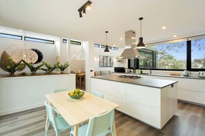 Una cocina moderna con una isla central, iluminación colgante y vistas al exterior.