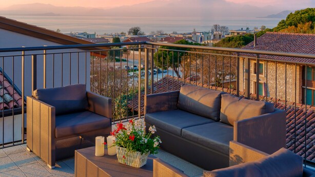 A balcony with a sofa, a small table, and a potted plant.