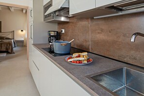 A modern kitchen with a built-in oven, a coffee machine, and a blue pot on the counter.