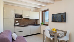 A compact kitchen with modern appliances, a dining area with a table and chairs, and a cozy seating area with a sofa.