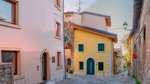 A narrow street with buildings on either side, a cobblestone path, and a small archway.