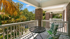 A covered outdoor area with a brick column, a round metal table, and a white railing.