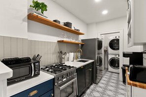 Une cuisine compacte équipée d’une cuisinière à gaz, d’un four à micro-ondes et d’un four encastré.