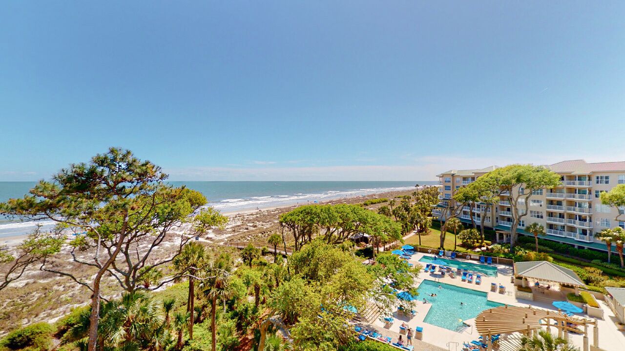 A resort with a pool area, beachfront view, and a multi-story building.