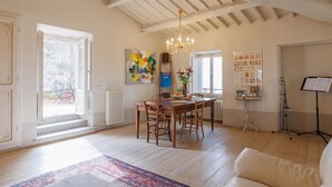 A dining area with a wooden table and chairs, a chandelier, and a radiator.