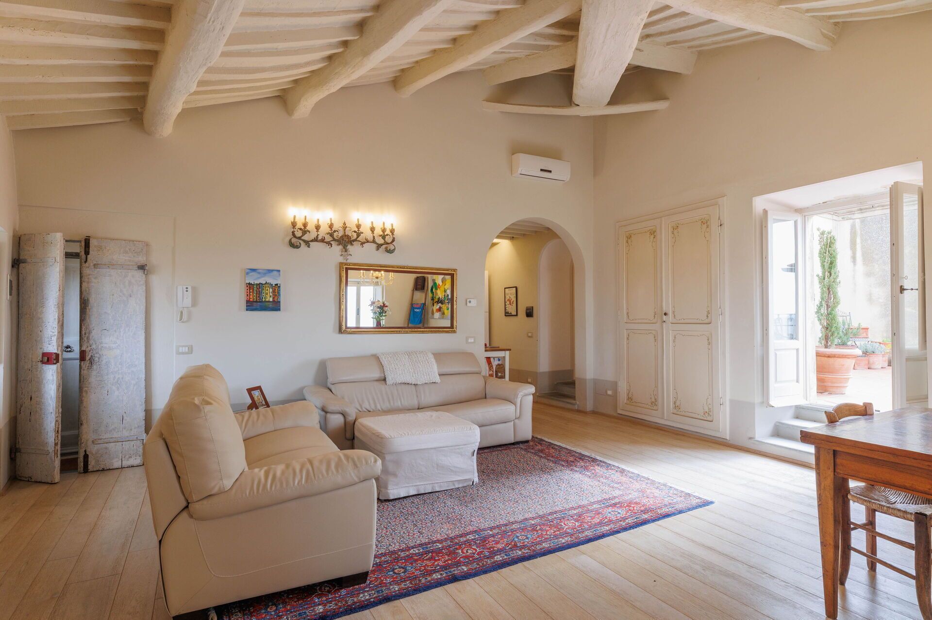 Un salon spacieux avec un grand canapé, un fauteuil plus petit, un tapis à motifs et une table en bois.
