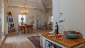 A spacious kitchen with wooden flooring, a chandelier, and a rustic ceiling.