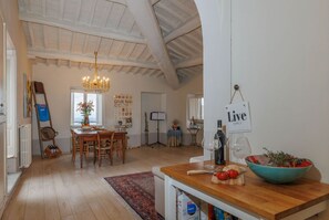 Una cocina amplia con una mesa de madera, una araña y un letrero que dice 'Live Simply'.