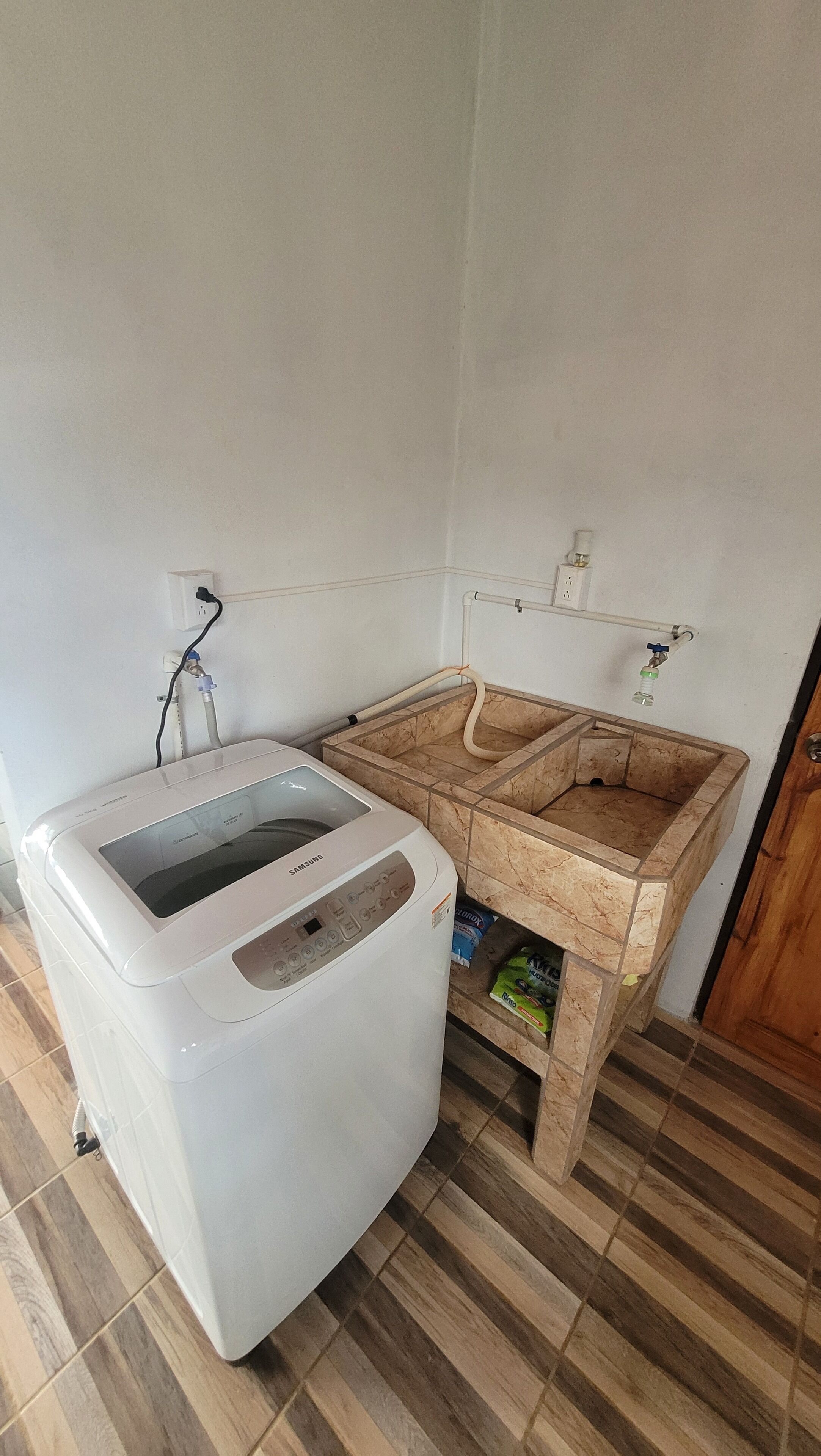 A compact room with a white washing machine, a marble sink, and a wooden cabinet.