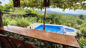An outdoor dining area with a pool and lush greenery.