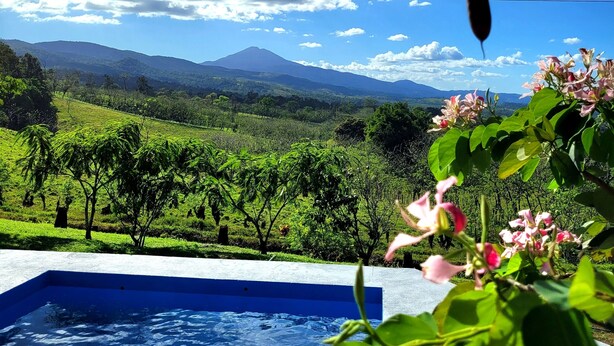Une piscine offrant une vue sur un paysage luxuriant et des montagnes en arrière-plan.