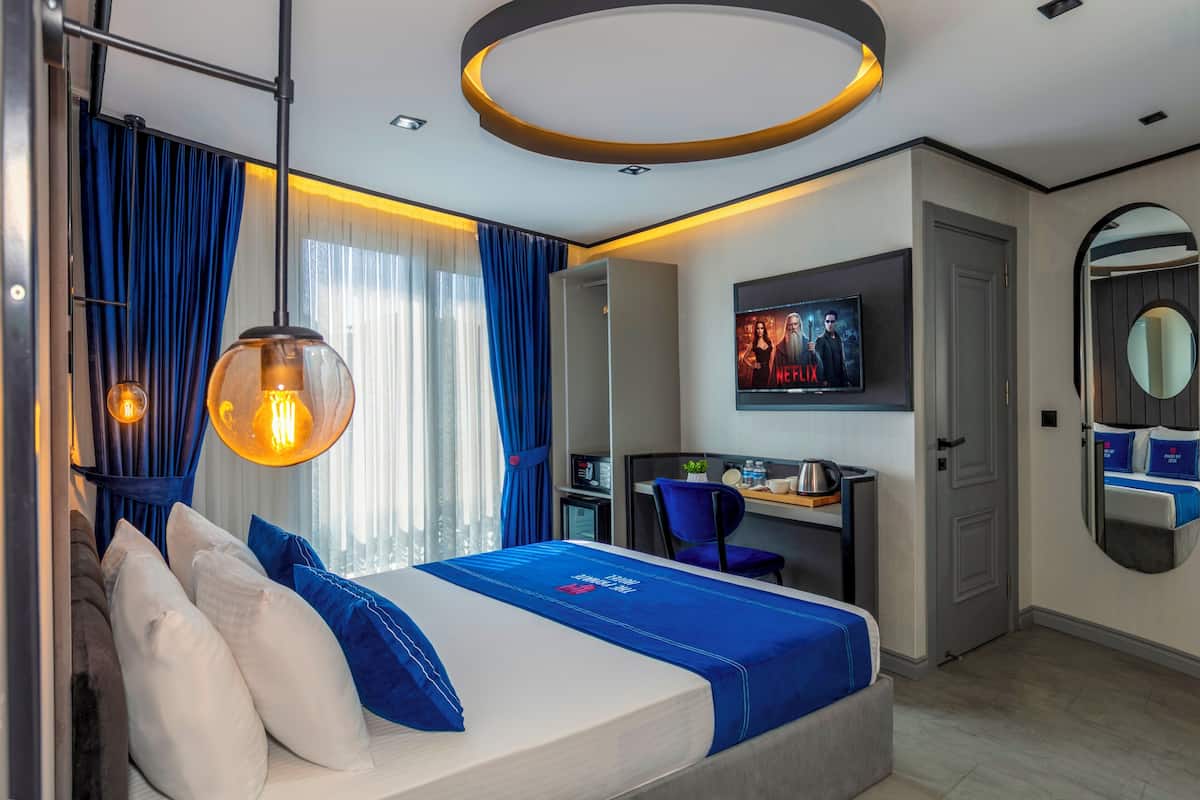 A modern hotel room with a bed, desk, and TV.