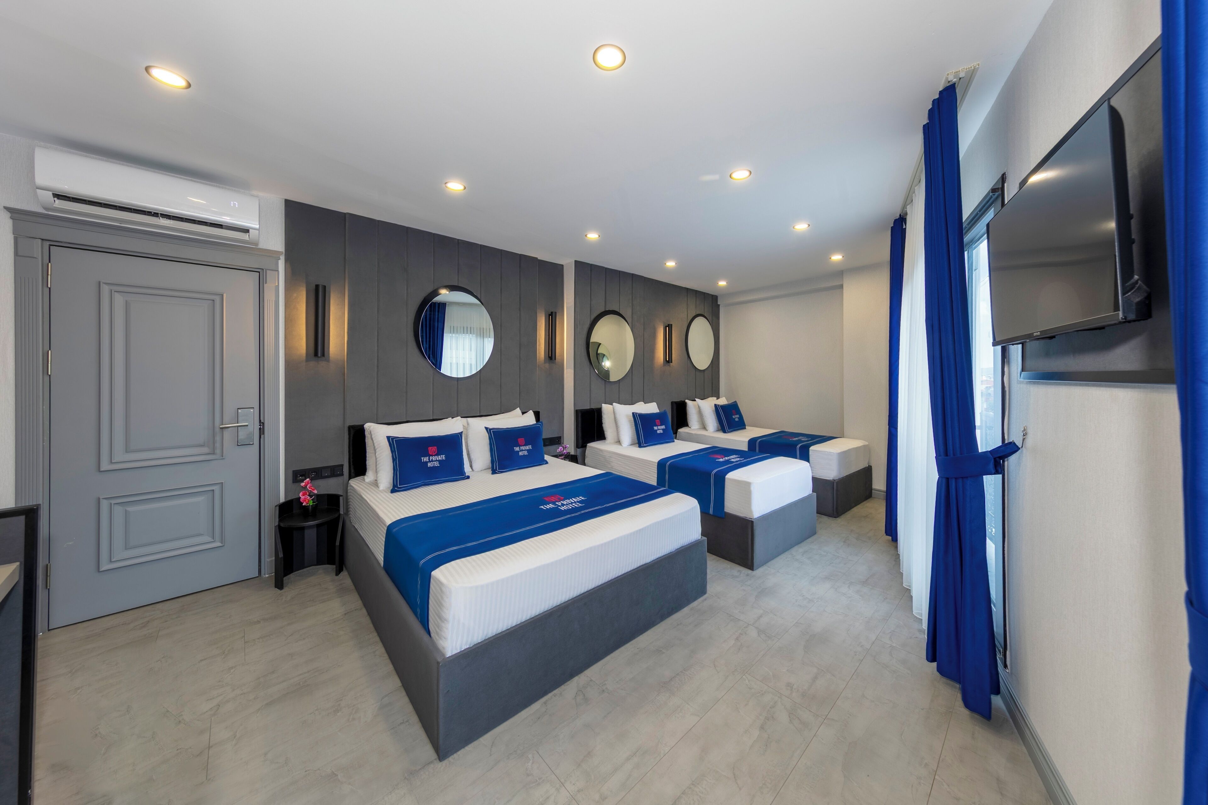 A hotel room with two beds, a TV, and a large mirror on the wall.