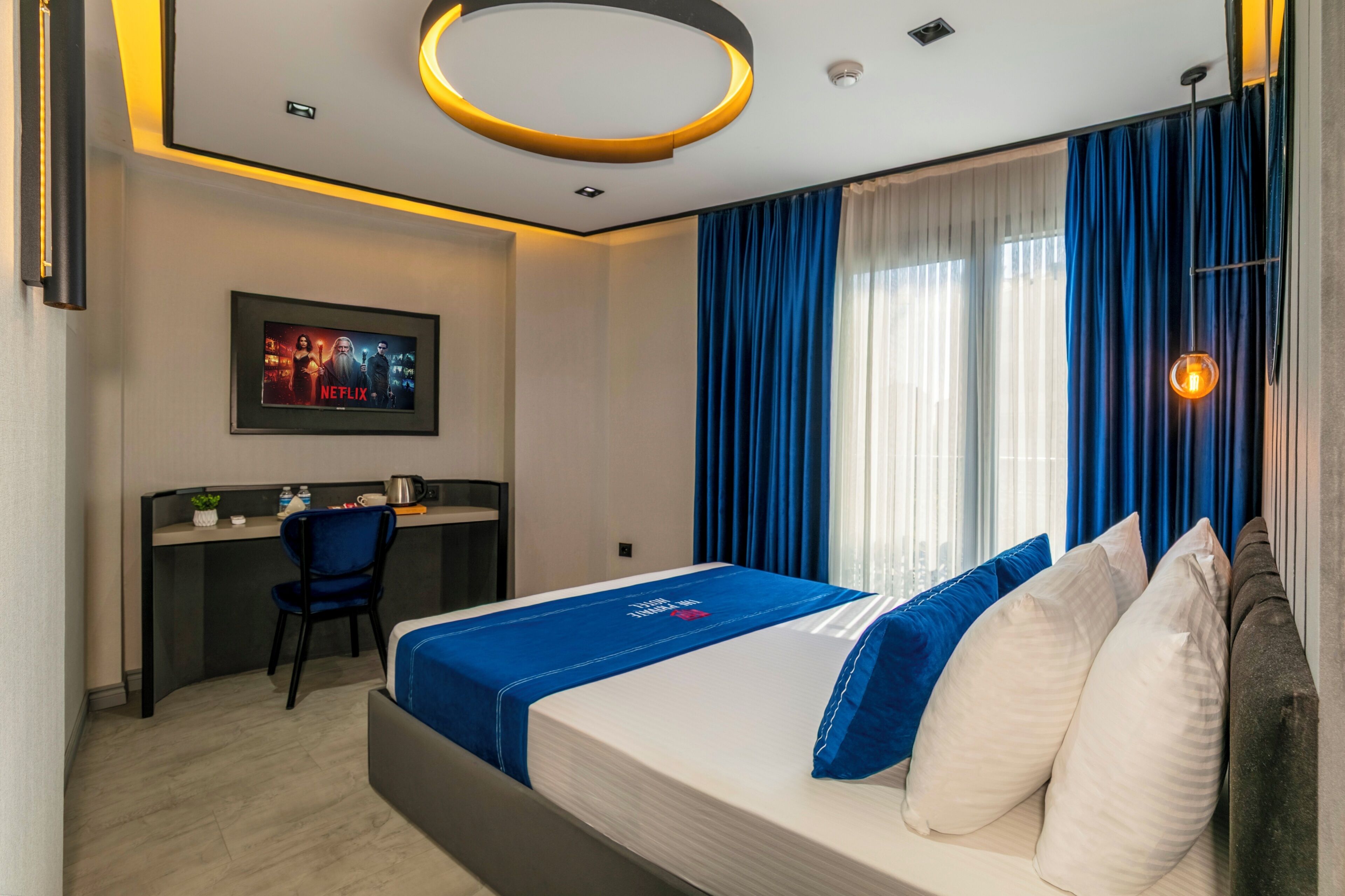 A hotel room with a bed, a desk, and a TV.