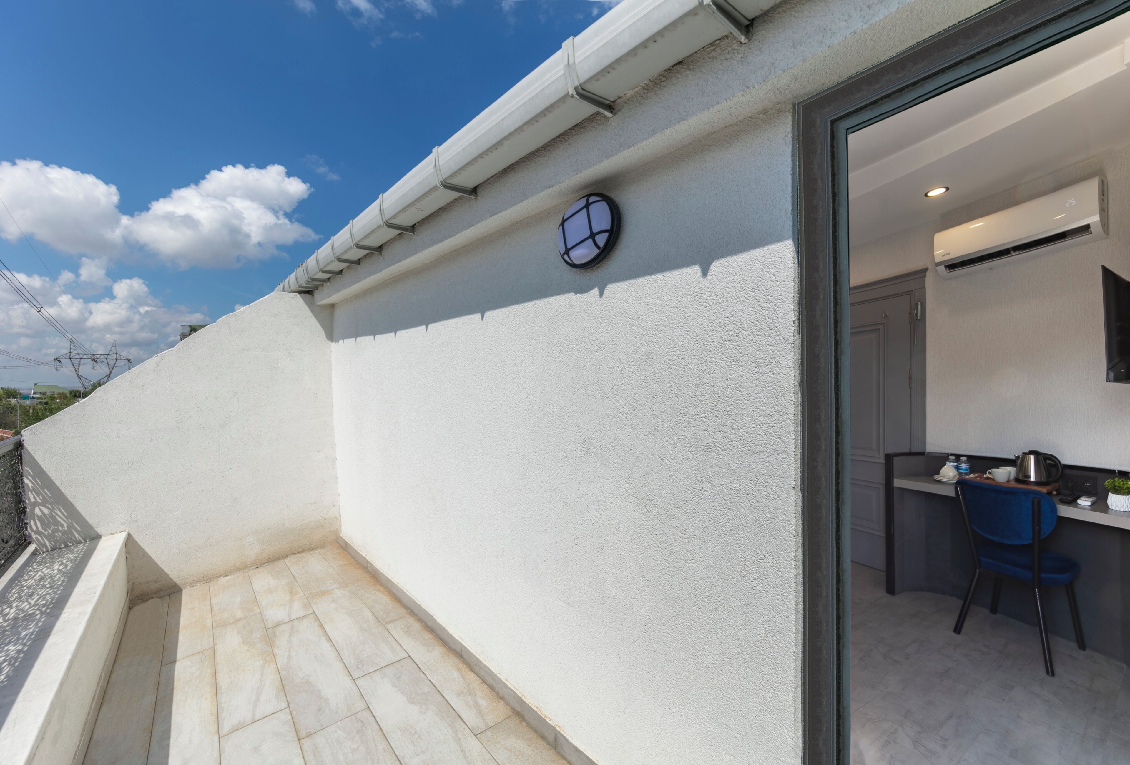 A modern apartment with a balcony, a kitchen area with a blue chair, and a clock on the wall.