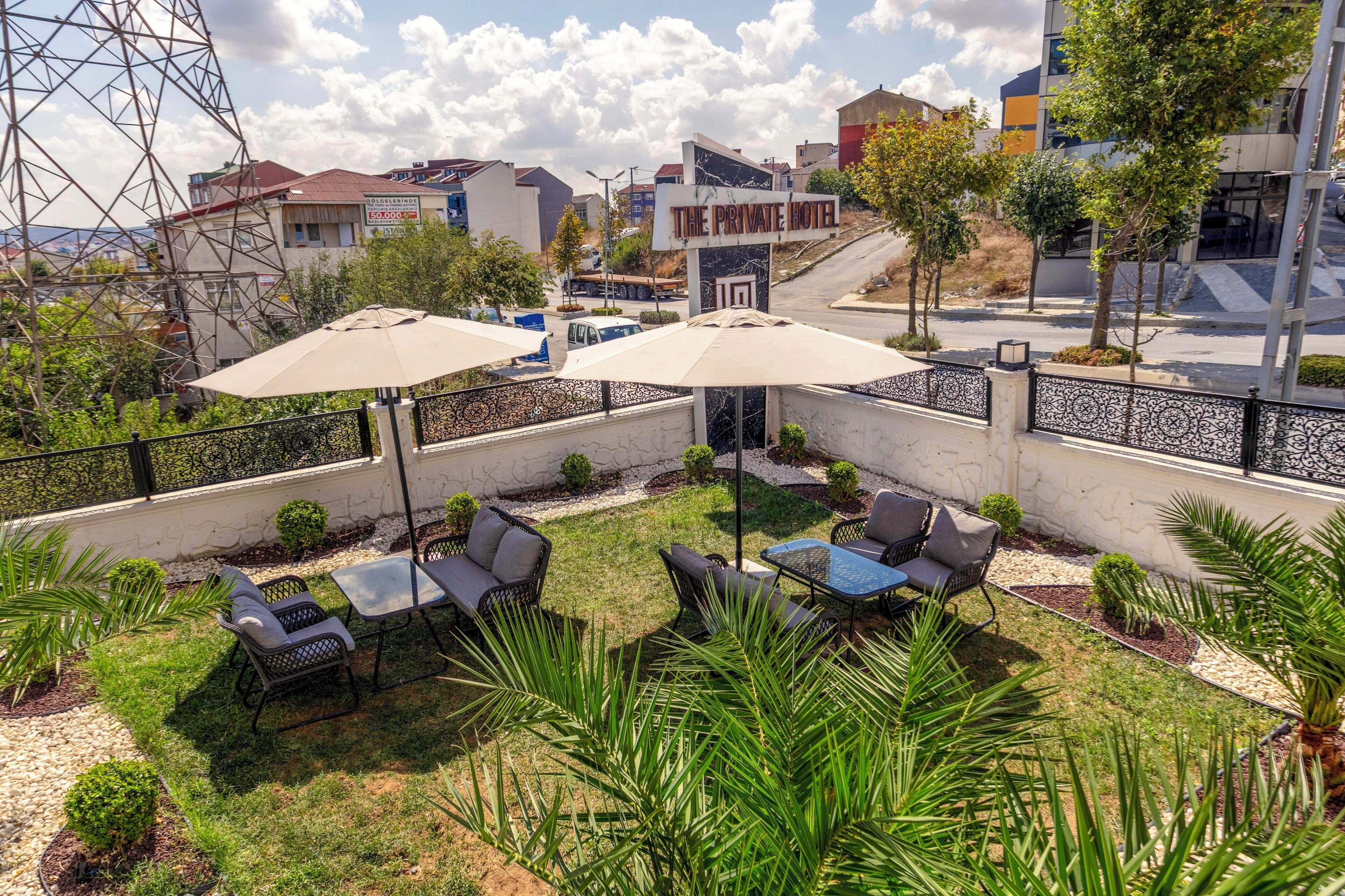 An outdoor patio with seating and umbrellas, a private hotel sign, and a view of the cityscape.