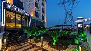 Privates Hotel mit gut beleuchtetem Eingang, Außenbereich zum Sitzen und angelegtem Garten.