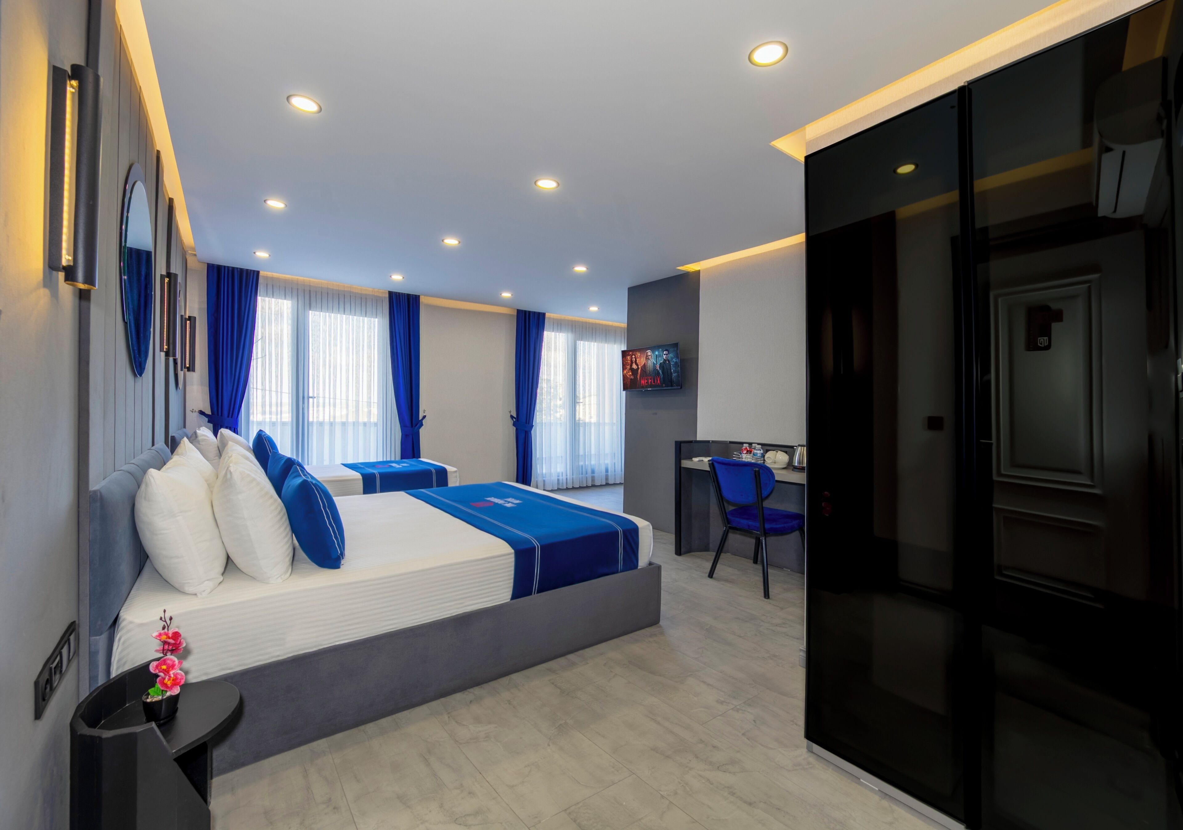A modern hotel room with a large bed, a desk, and a TV.