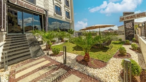 Privates Hotel mit gepflegtem Garten, Sitzgelegenheiten im Freien und freiem Blick auf den Haupteingang des Gebäudes.