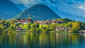 A lakeside resort with multiple chalet-style buildings, a mountain backdrop, and a calm lake reflecting the scenery. - Appartment mit Balkon und Seeblick (Grundlsee)