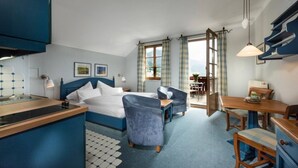 A hotel room with a bed, a desk, a chair, a dining table, and a view of the outdoors. - Appartment mit Balkon und Seeblick (Grundlsee)