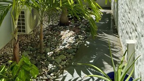 A narrow pathway lined with palm trees and a small potted plant, surrounded by a white wall and a concrete structure. - C'EST LA VIE !PRIVATE POOL AND AMAZING VIEWS ON PINEL ISLAND AND PETITE CLEF🌴 (Cul de sac)