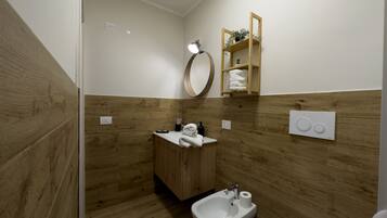Un baño moderno con paneles de madera, un mueble de tocador de madera, un lavamanos, un bidé y un inodoro.