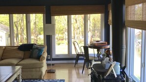 A cozy living room with a large window, a fireplace, a sofa, and a dining table. - Nashville/Old Hickory Lake cottage (Mt. Juliet)