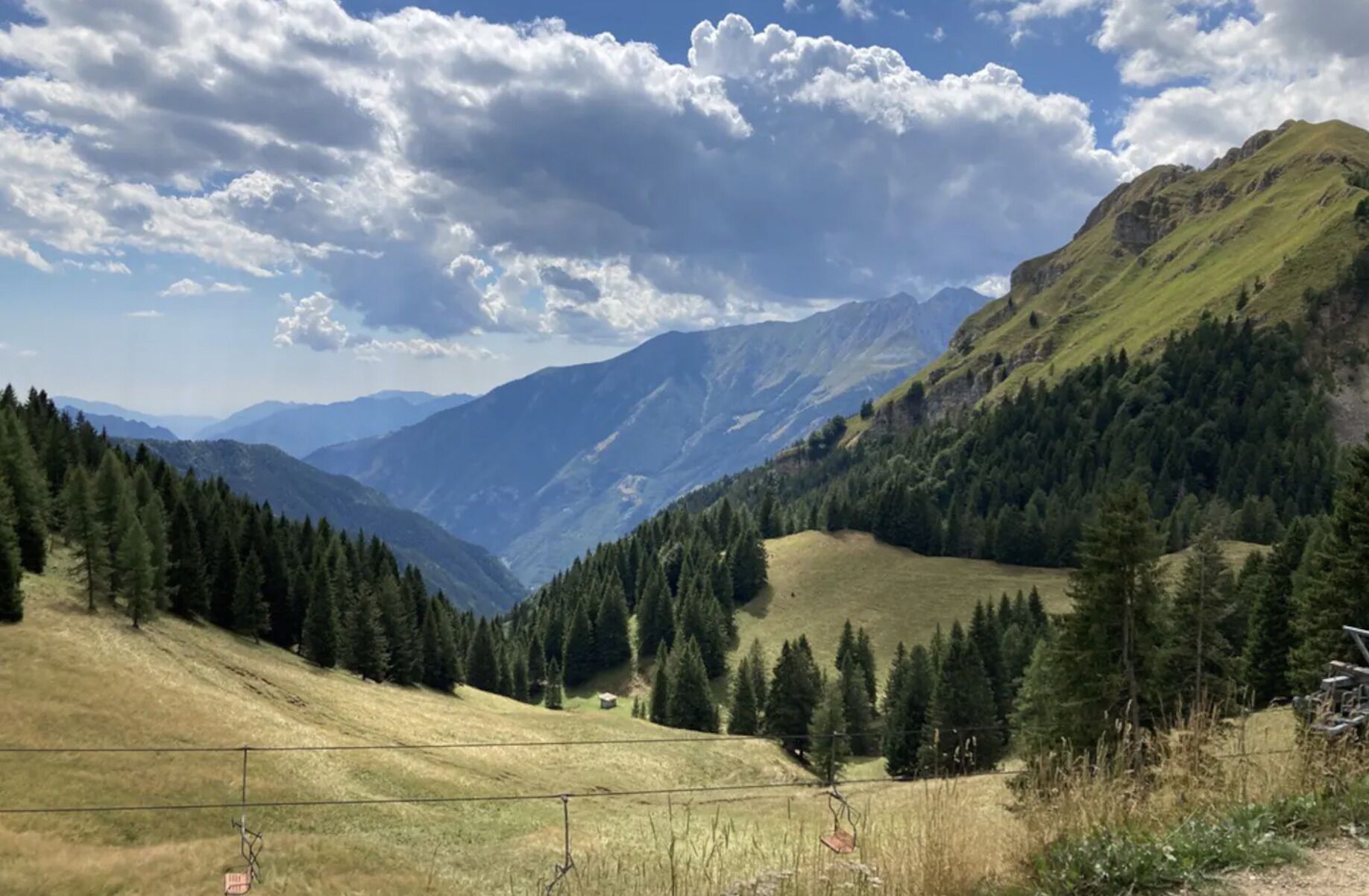A mountainous landscape with a valley, dense forest, and a clear sky.