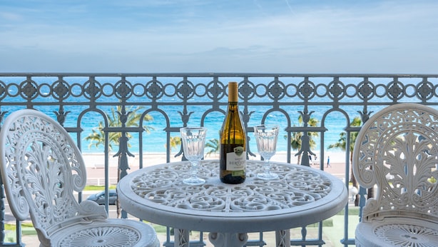 A round table with a bottle of wine and two glasses, set on a balcony overlooking the sea. - Happyfew Palazzo del sol (Nice)