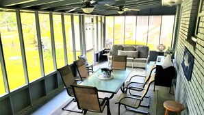 A sunlit patio with a dining table, chairs, and a sofa.