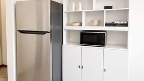 Eine Küche mit Edelstahl-Kühlschrank, Mikrowelle und weißen Schränken.