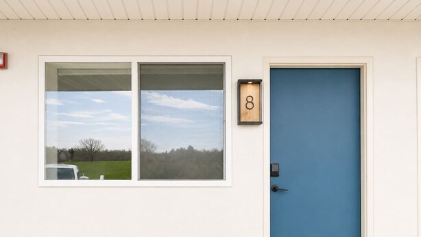 Ein Gebäude mit einer blauen Tür, einem Schild mit der Nummer 8 und zwei Fenstern.