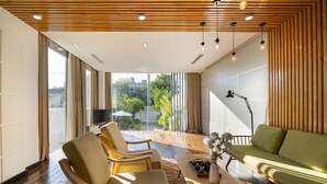 Un salon moderne avec un canapé vert, deux fauteuils, une table basse et un téléviseur.