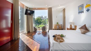 Une chambre d’hôtel avec un grand lit, une télévision, un balcon donnant sur un espace verdoyant et une porte rouge.