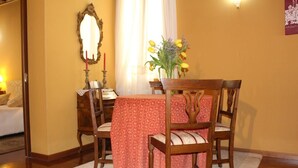 Un comedor con una mesa dispuesta para cuatro personas, un espejo y un florero con flores.