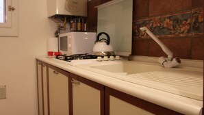 Una cocina con estufa, hervidor y microondas.