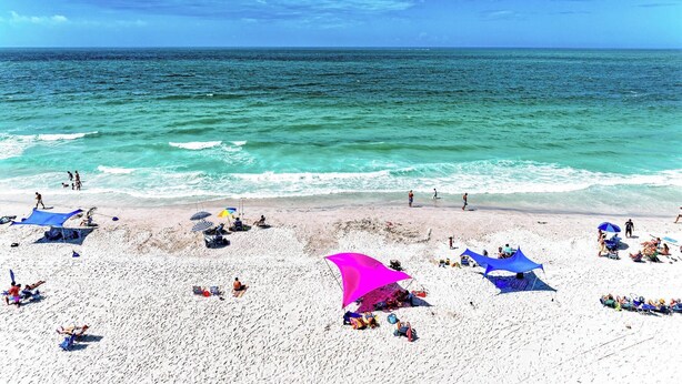 A beach with white sand, clear turquoise water, and people sunbathing. - La Casa Marie - 3 Bedroom Luxury Condo in Beachfront Complex - Anna Maria - By I (Holmes Beach)