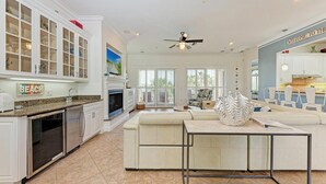 A spacious kitchen with white cabinetry, a built-in oven, and a dining area with a white sofa and a table. - La Casa Marie - 3 Bedroom Luxury Condo in Beachfront Complex - Anna Maria - By I (Holmes Beach)