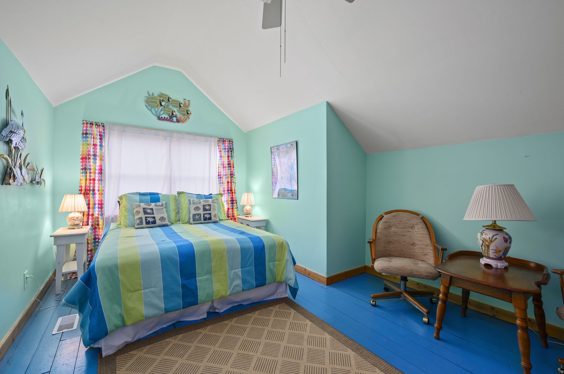 A bedroom with a bed, a chair, a table, and a window.
